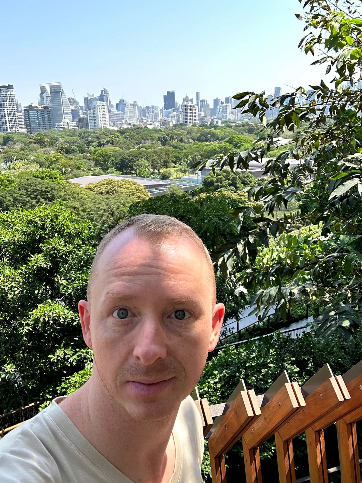 Dennis op een terras met een groen park en de skyline van Bangkok op de achtergrond.