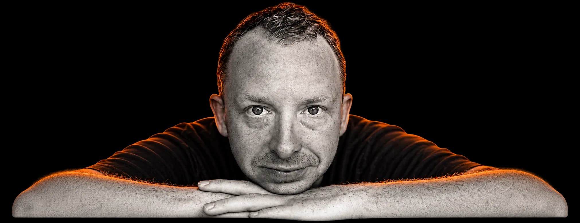 Dennis Haxe kijkt in de camera met zijn kin op zijn handen.